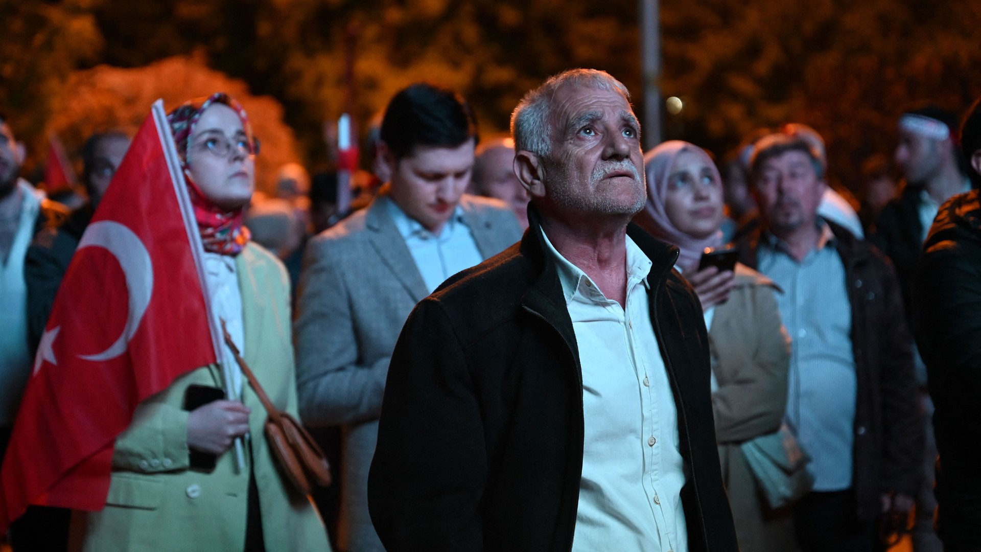 Supporters of Recep Tayyip Erdogan look at early presidential election results displayed on a screen at AK Party headquarters in Istanbul on 14 May (AFP)