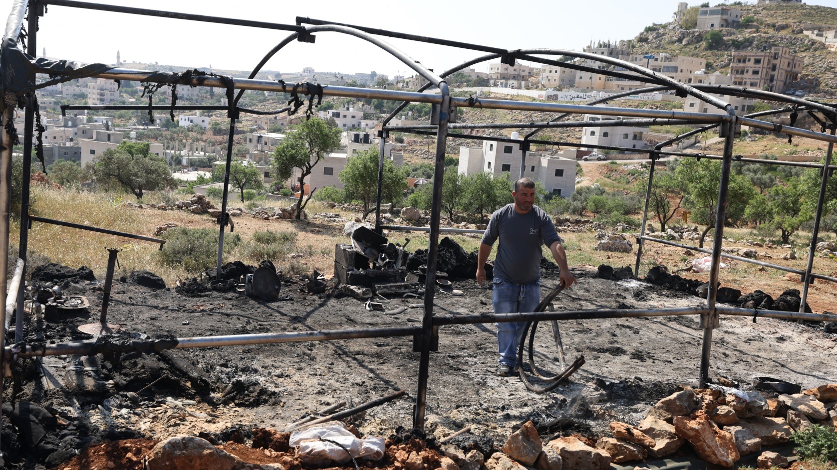 A Palestinian inspects the damage in the village of Mughayir near Ramallah in the Israeli-occupied West Bank on 13 April, 2024, after an attack by Israeli settlers on the village (AFP)