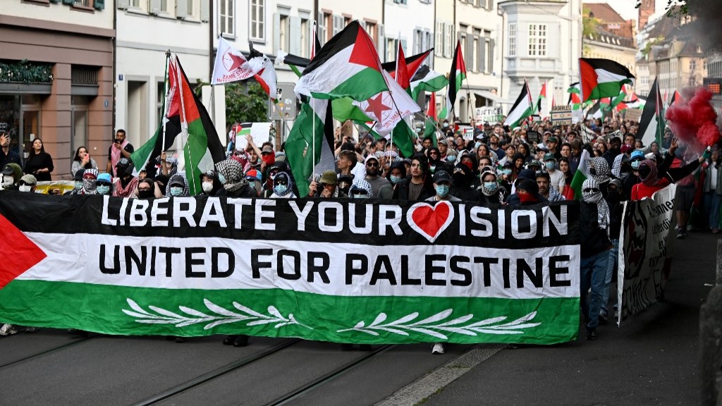 Protestors hold a banner and Palestinian flags during a demonstration against Israel's candidate prior to the grand final of the Eurovision Song Contest 2025 in Basel on May 17, 2025 (AFP) 