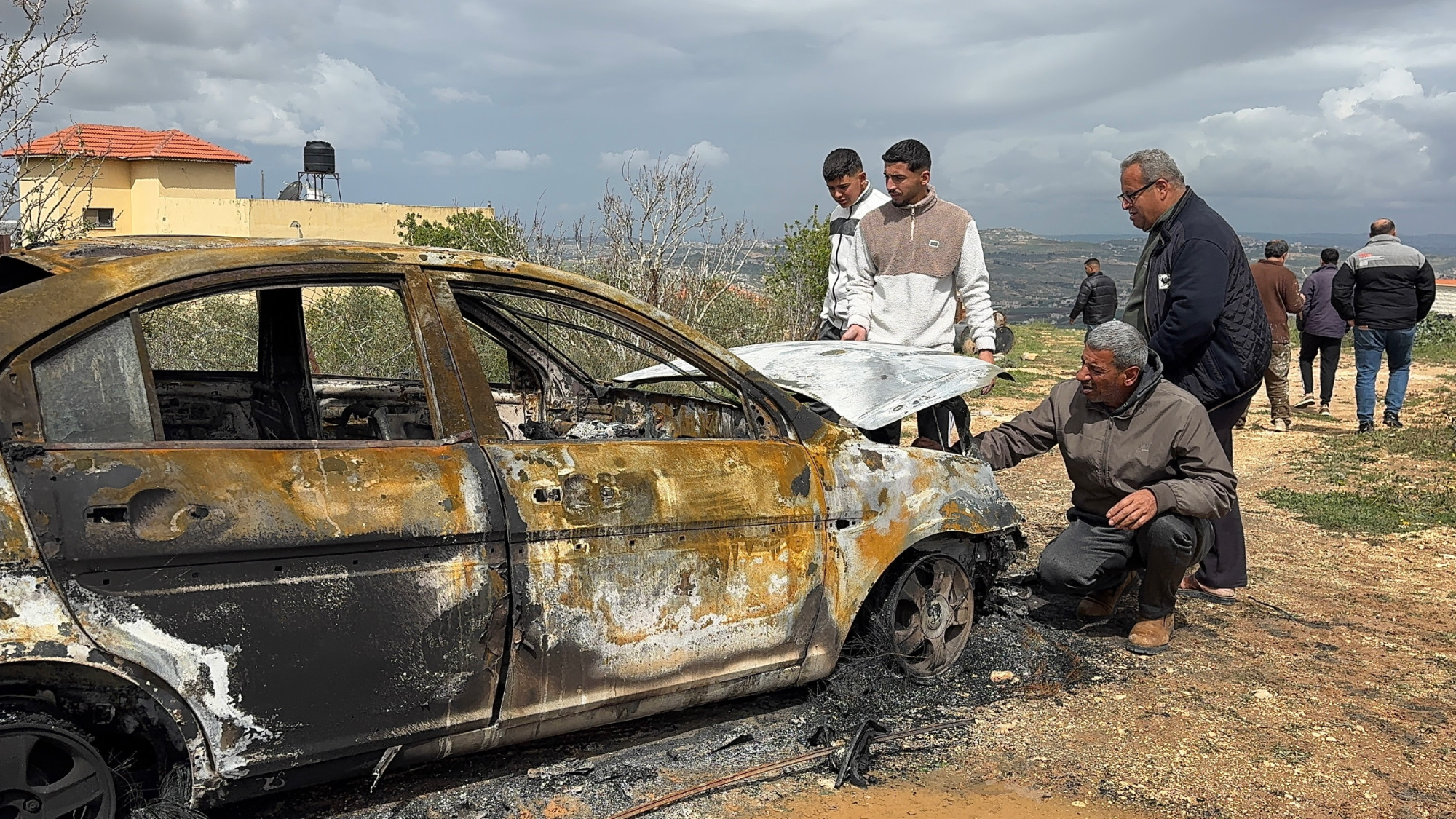 Palestinians inspect a car burned by Israeli settlers in the occupied West Bank on 21 March 2026 (MEE/Mohammed Atiq)
