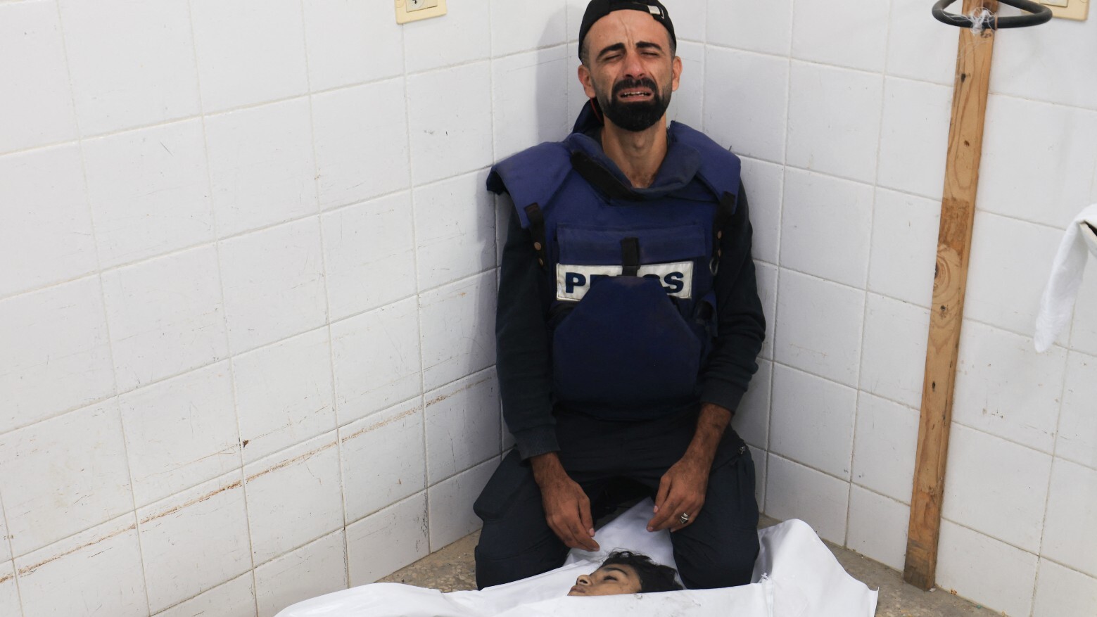 Palestinian cameraman Mohammed Alaloul mourns over the body of his son killed in an Israeli strike on 5 November 2023 (AFP)