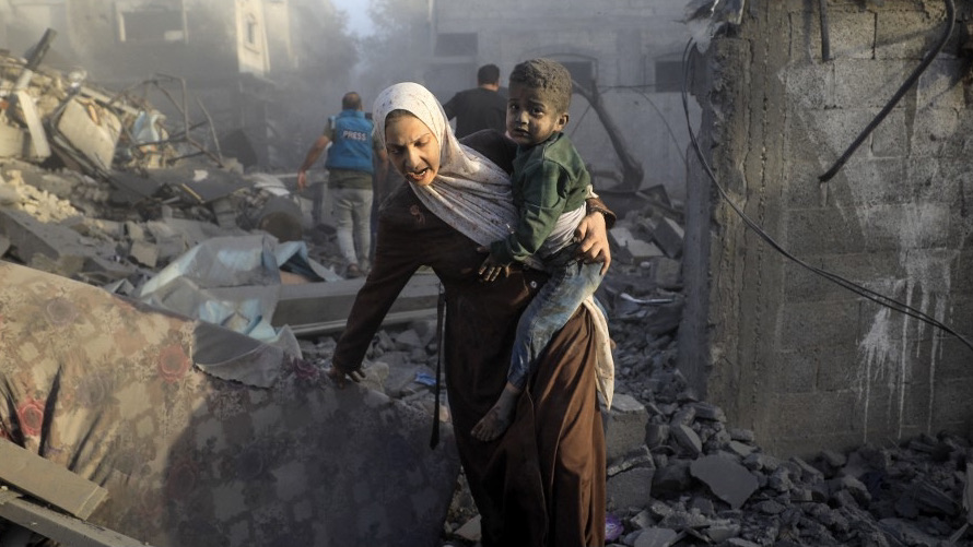 A woman flees with a child following Israeli air strikes on the al-Maghazi refugee camp in the central Gaza Strip on 6 November 2023 (Yasser Qudhi/AFP)