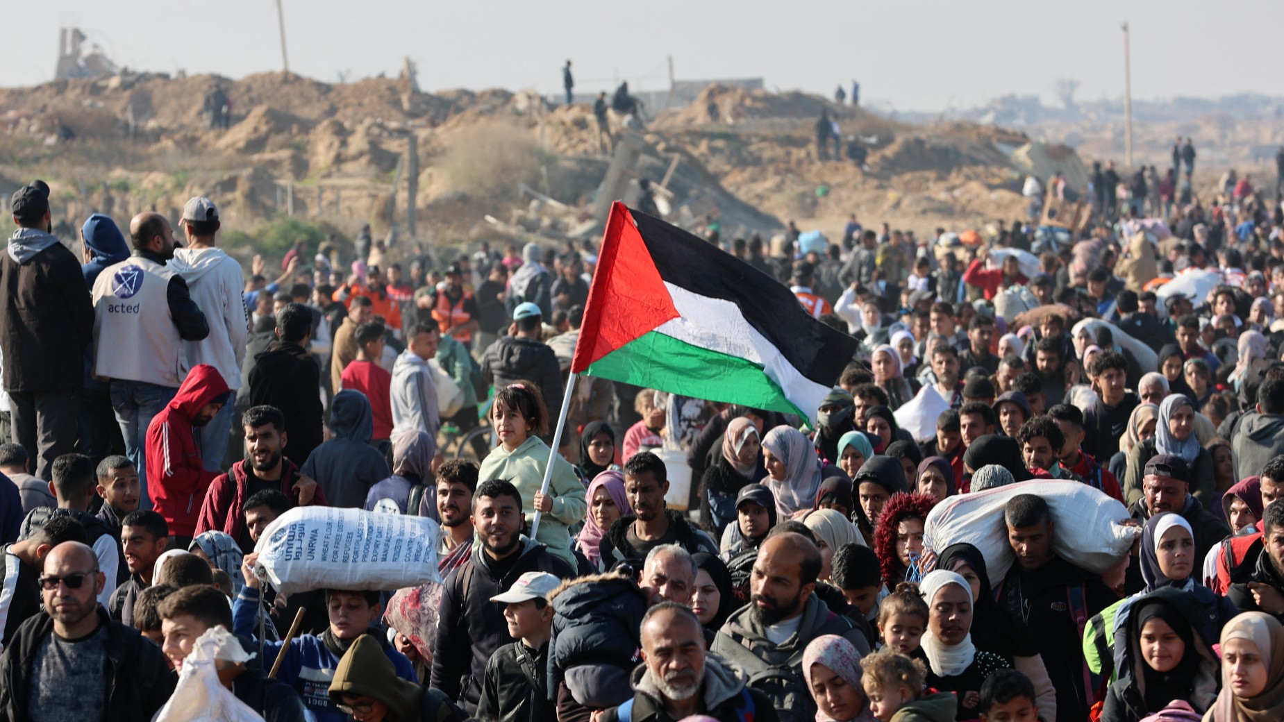 People walk along Gaza's coastal al-Rashid Street to cross the Netzarim corridor from the southern Gaza Strip into the north on 27 January, 2025 (AFP)