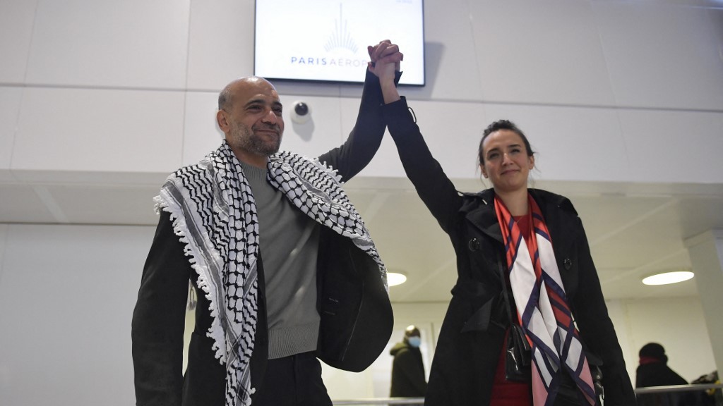 Egyptian-Palestinian political activist Ramy Shaath holds hands with his wife, Celine Lebrun-Shaath, after arriving at Roissy airport outside Paris on 8 January 2022 (AFP)