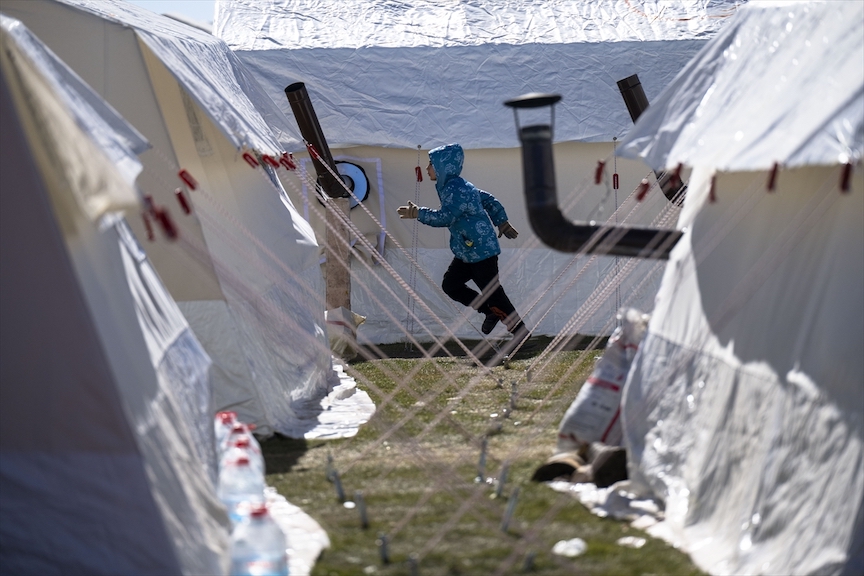 A child runs amid tents at the Sumerevler Athletics Track, turned into a tent city for quake survivors on 16 February 2023 (Anadolu Agency)