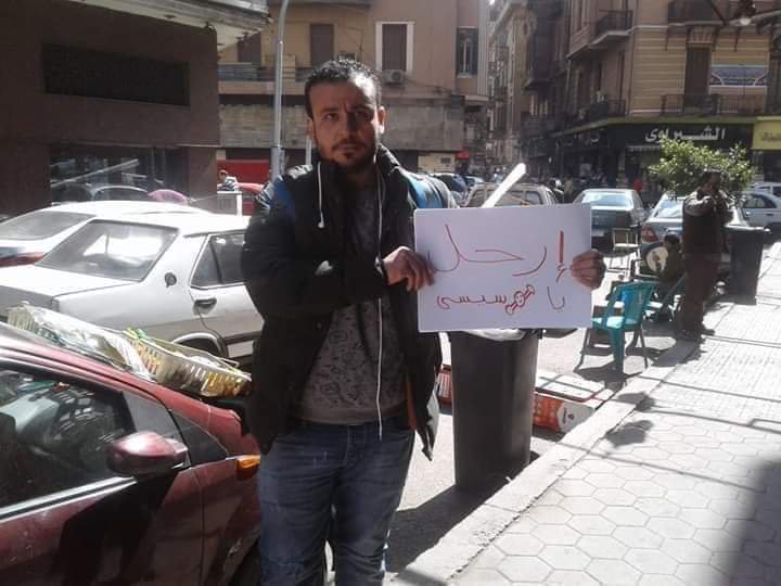 Ahmed Mohy holds a sign reading 