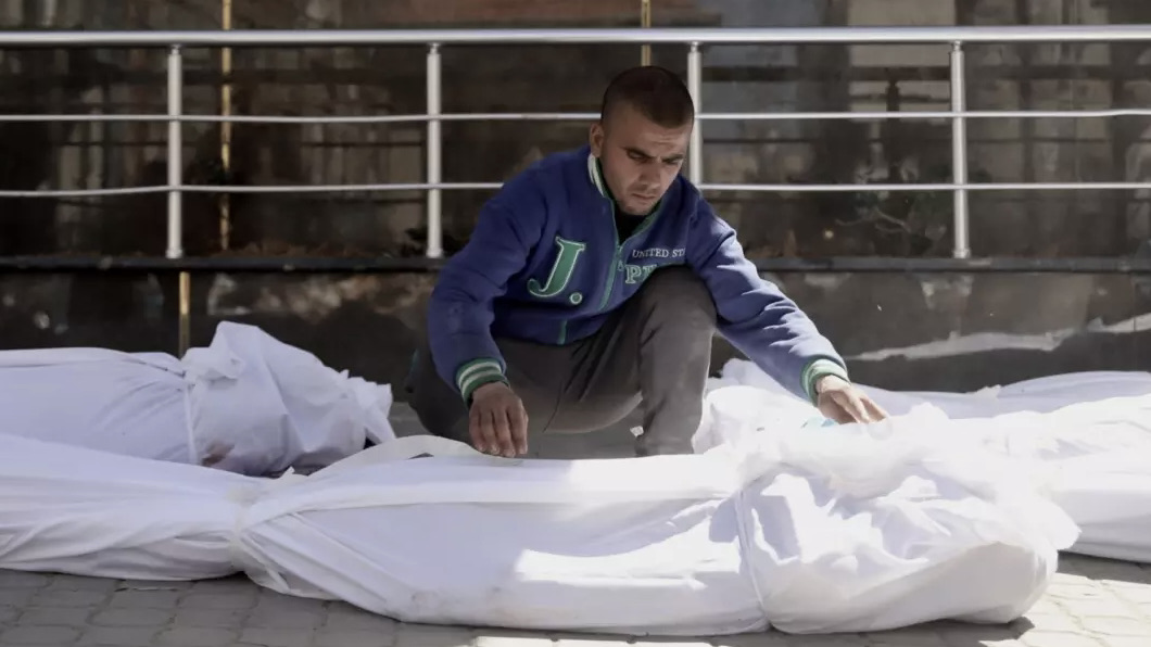 A man at al-Shifa Hospital attends to a body following Israel's attack on people in Gaza City as they queued for food, 1 March 2024 (Mohammed al-Hajjar/MEE)