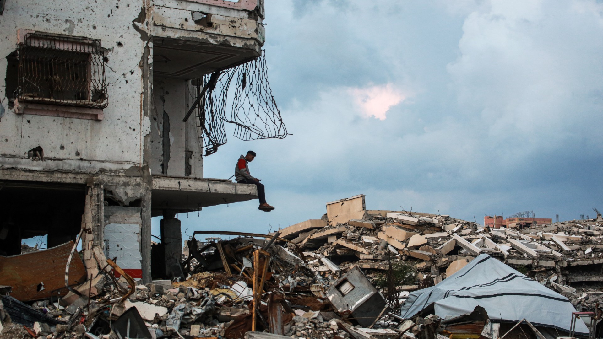 A man sits on the edge a destroyed building in the Al-Saftawi neighborhood, west of Jabalia city in the northern Gaza Strip on 10 December 2025 (AFP/Bashar Taleb)