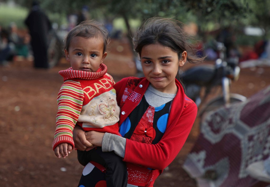 Displaced Syrian children gather near a camp in Idlib province on 8 May (AFP)