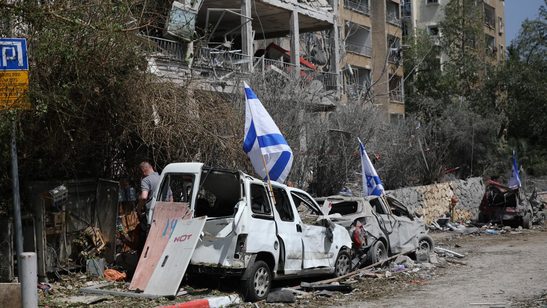 Israeli forces plant their country's flags on cars damaged by Iranian air strikes on Tel Aviv, on 14 June 2025 (MEE/Faiz Abu Rmeleh)