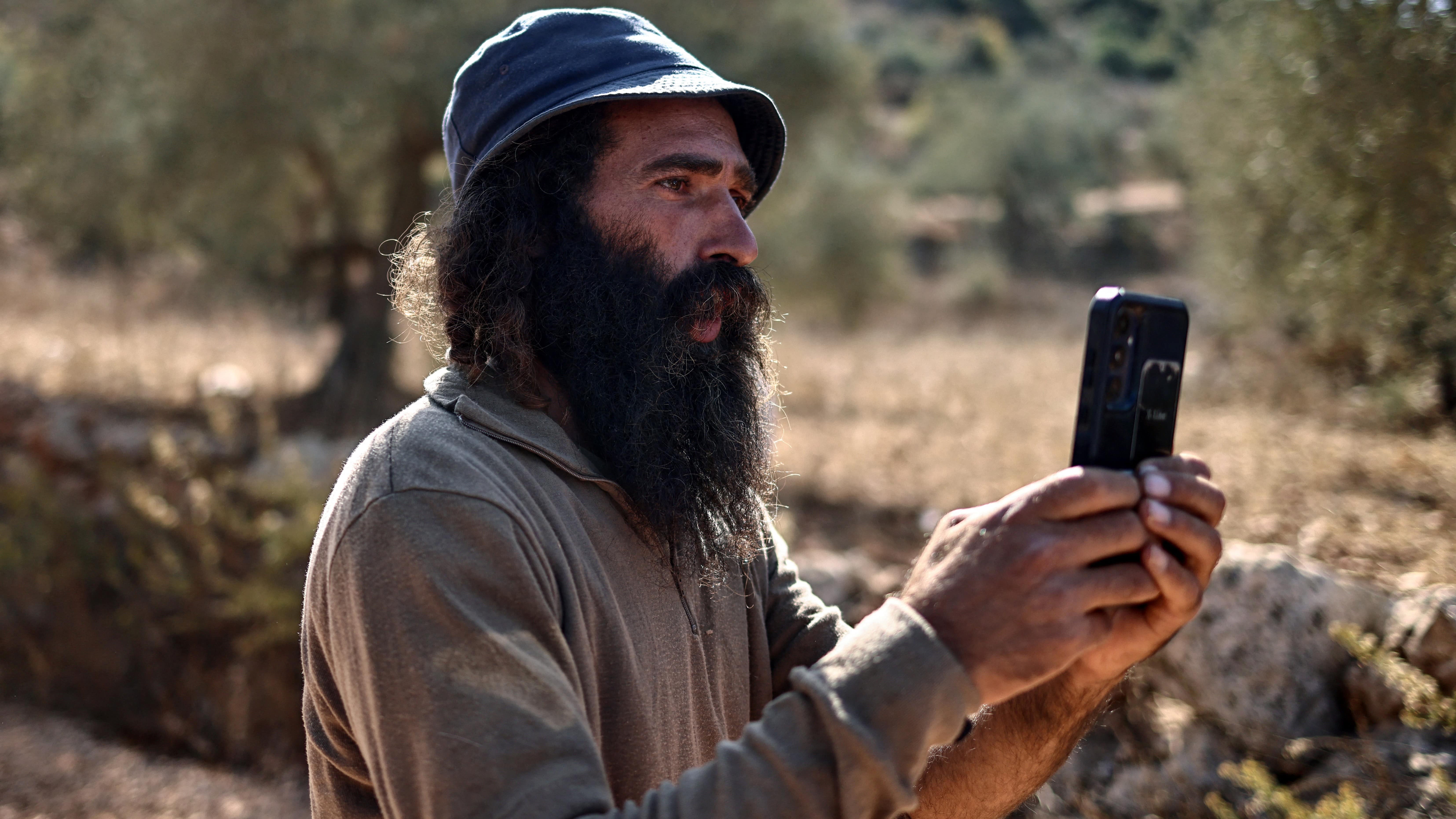An Israeli settler disrupts a Palestinian farmer's olive harvest near the occupied West Bank village of Turmus Ayya, 28 October 2025 (Zain Jaafar/AFP)