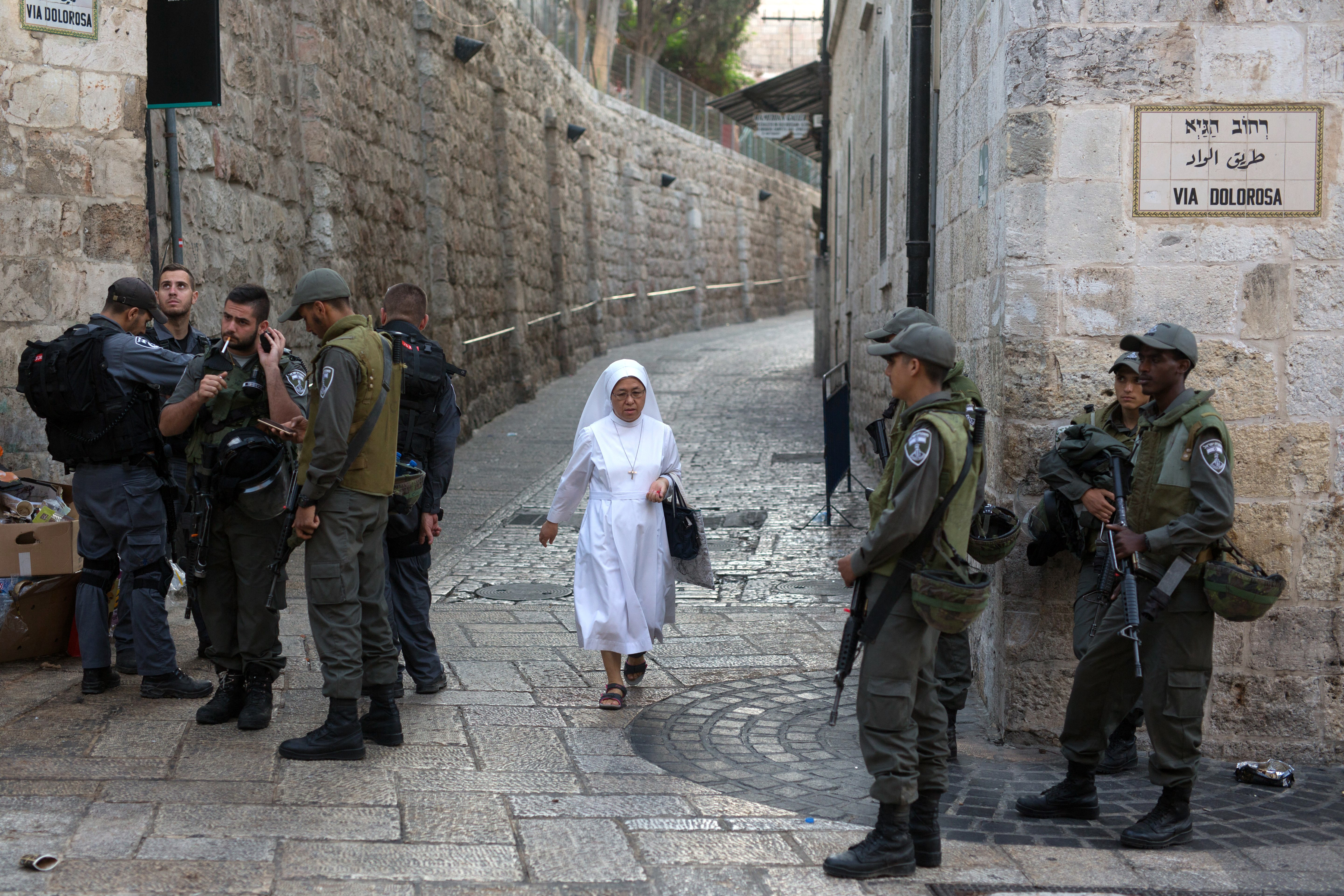 A nun walks past Israeli police on Via Dolorosa in the Old City of Jerusalem (AFP/Menahem Kahana)