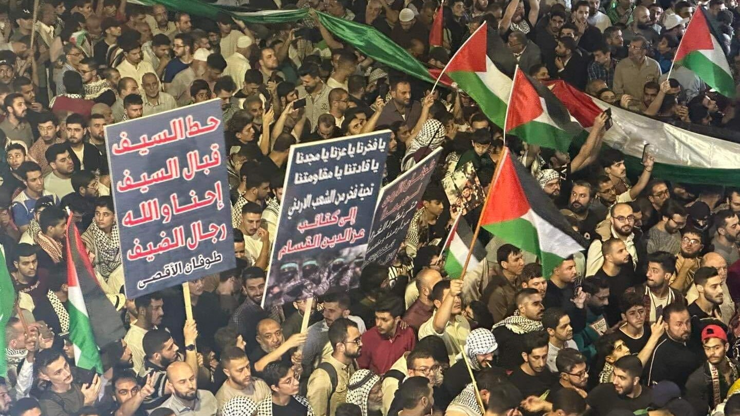 Jordanians wave the Palestinian flag and chant slogans against Israel as they gather in Amman on 10 October 2023 to express their support for Gaza (MEE/Mohammad Ersan)