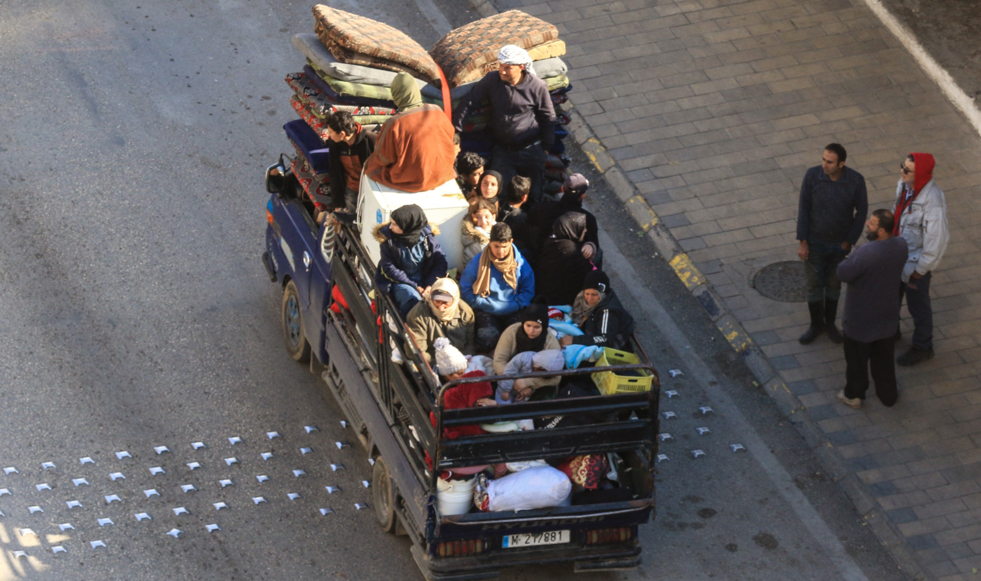 A family flee their village in southern Lebanon, riding in the back of a truck along the coastal road through the city of Saida on 2 March 2026 (AFP)