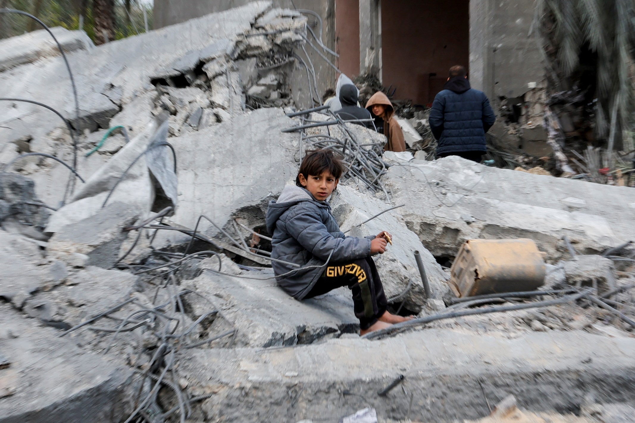 A boy sits amid rubble as Palestinians inspect the site of an Israeli strike on a house in Khan Younis, south Gaza, on 20 March, 2025 (Reuters/Hatem Khaled)