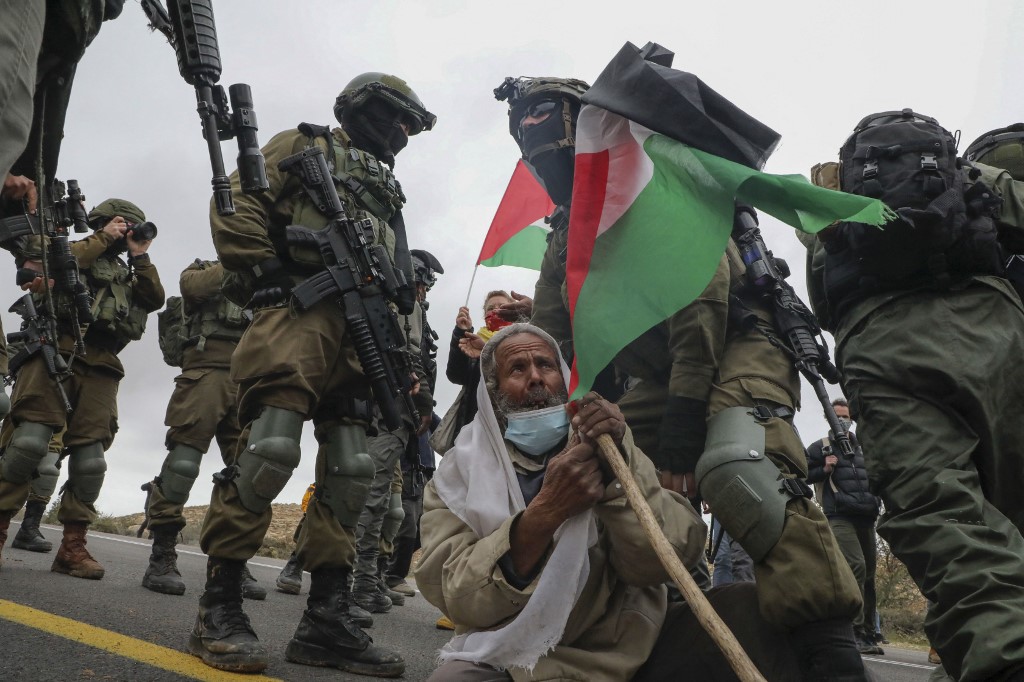 Israeli soldiers arrest an elderly Palestinian man taking part in a demonstration against settlements, near Yatta village, south of Hebron in the occupied West Bank, on 15 January 2021 (AFP)