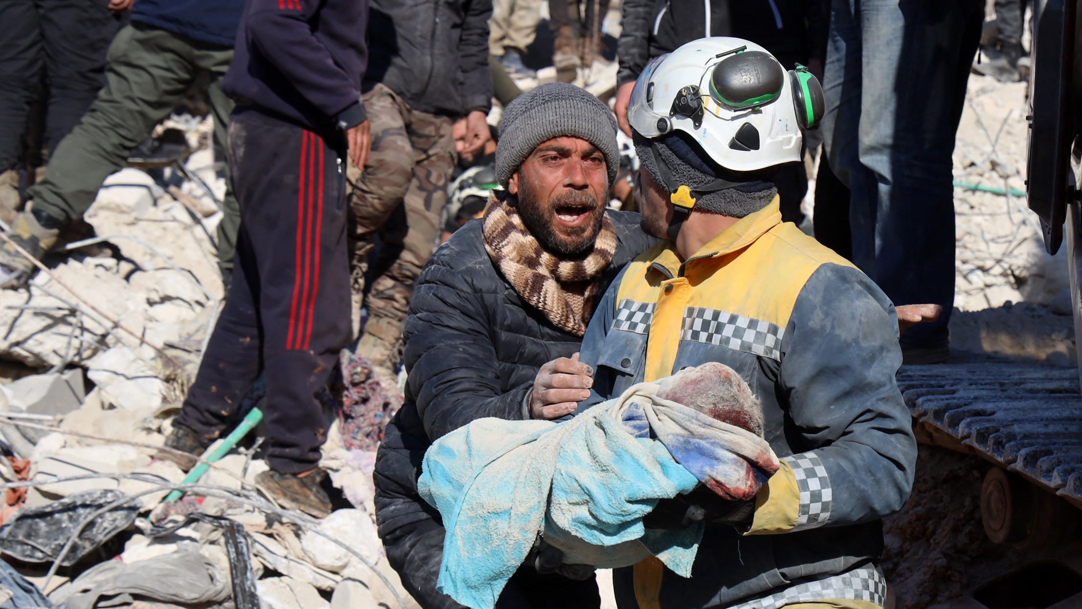 A man reacts as the body of his baby is pulled out from the rubble by a White Helmet's rescue worker in the town of Harim in Syria's rebel-held northwestern Idlib province on 8 February 2023 (AFP)