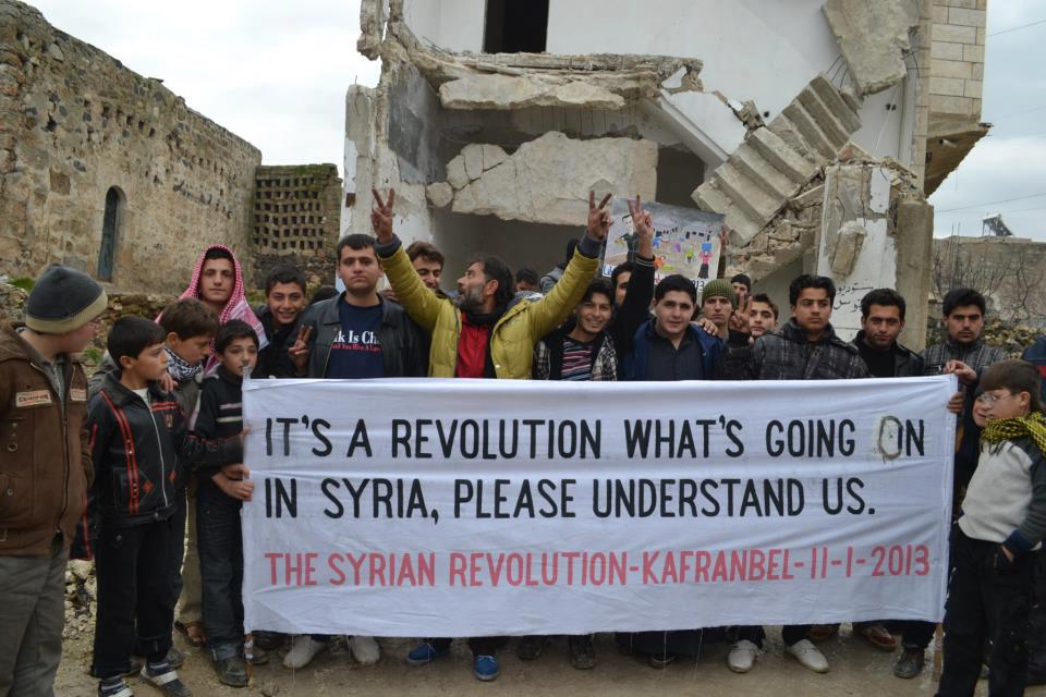 Kafranbel activists hold up a banner in support of the Syrian revolution in 2013 (Facebook)