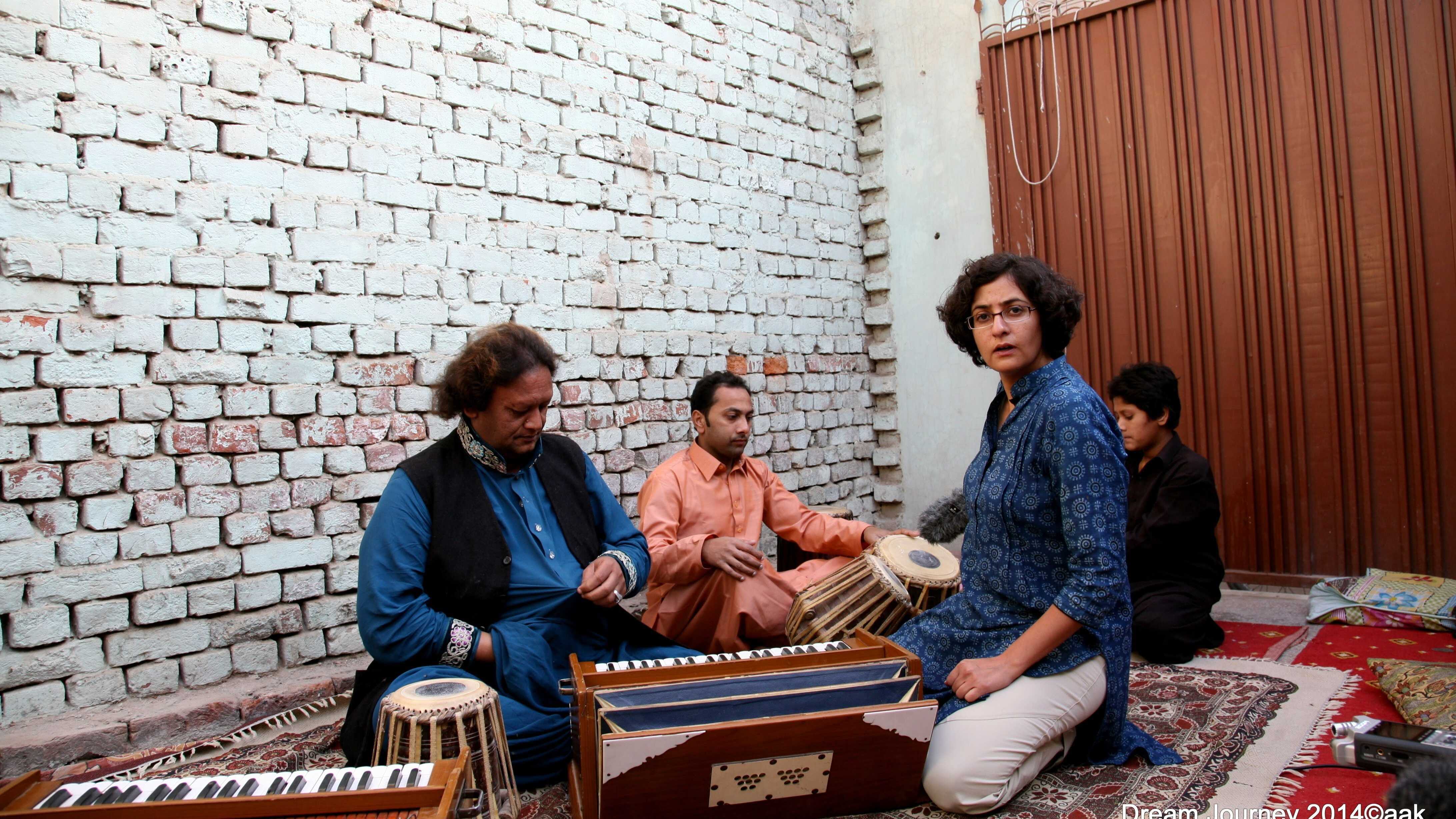 Ustad Ameer Ali Khan sits by the harmonium as Dream Journey filmmaker Mahera Omar looks at the camera.