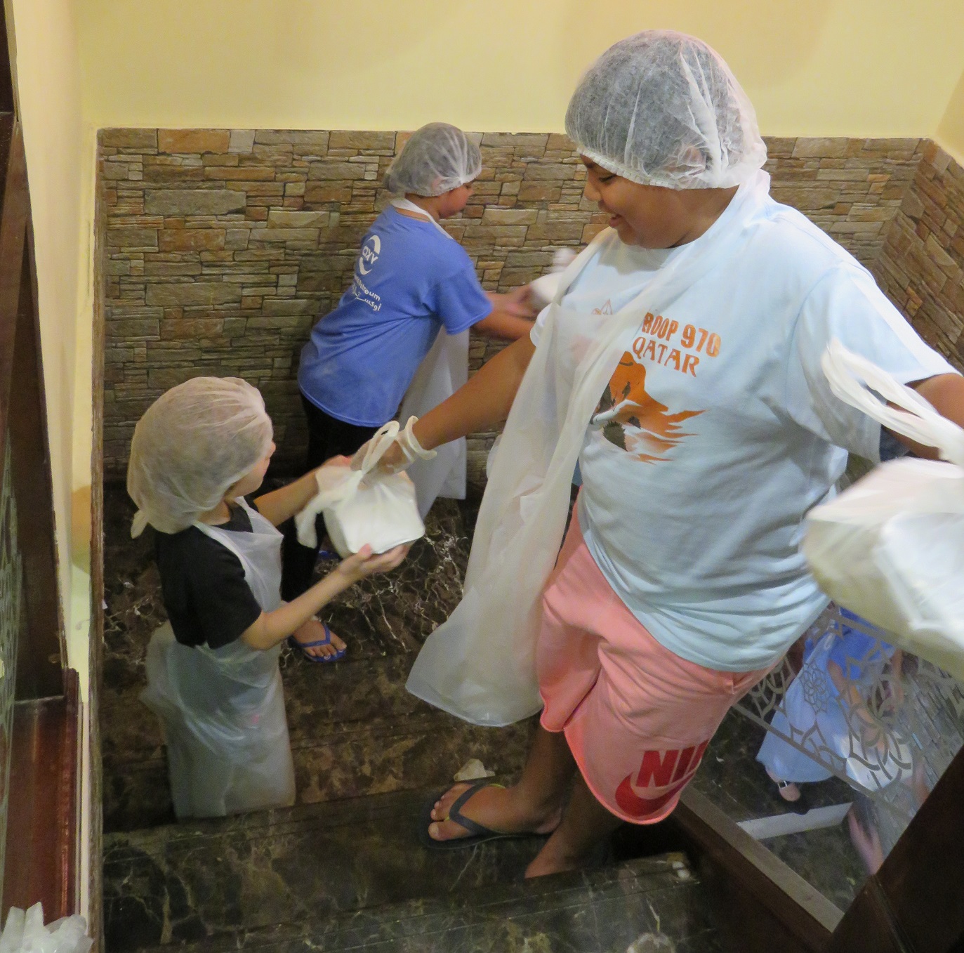 Au restaurant Malabar à Doha, les enfants aident leurs parents à préparer des repas gratuits en faisant passer les assiettes jusqu’au rez-de-chaussée (MEE/Roxanne D’Arco)