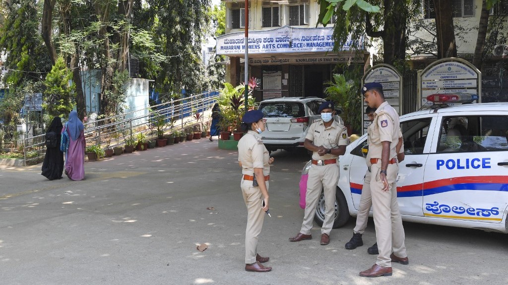 Women wearing veils walk past police guarding a school in Bangalore, India, on 15 March 2022, after an Indian court upheld a local ban on the hijab in classrooms (AFP)
