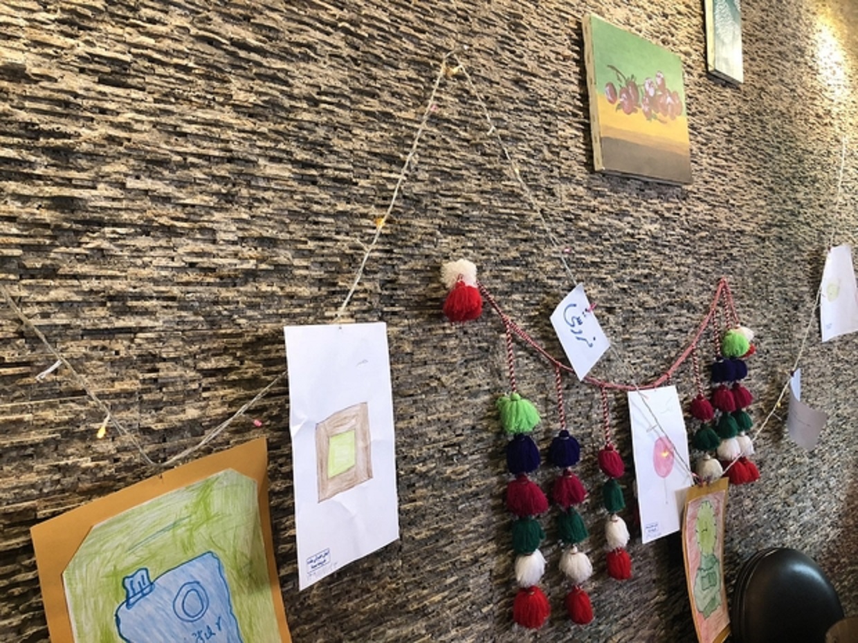Des photos et des bijoux fabriqués par des membres du personnel sont accrochés aux murs du café et vendus pour aider à financer les coûts de fonctionnement (MEE/Sahar Esfandiari)
