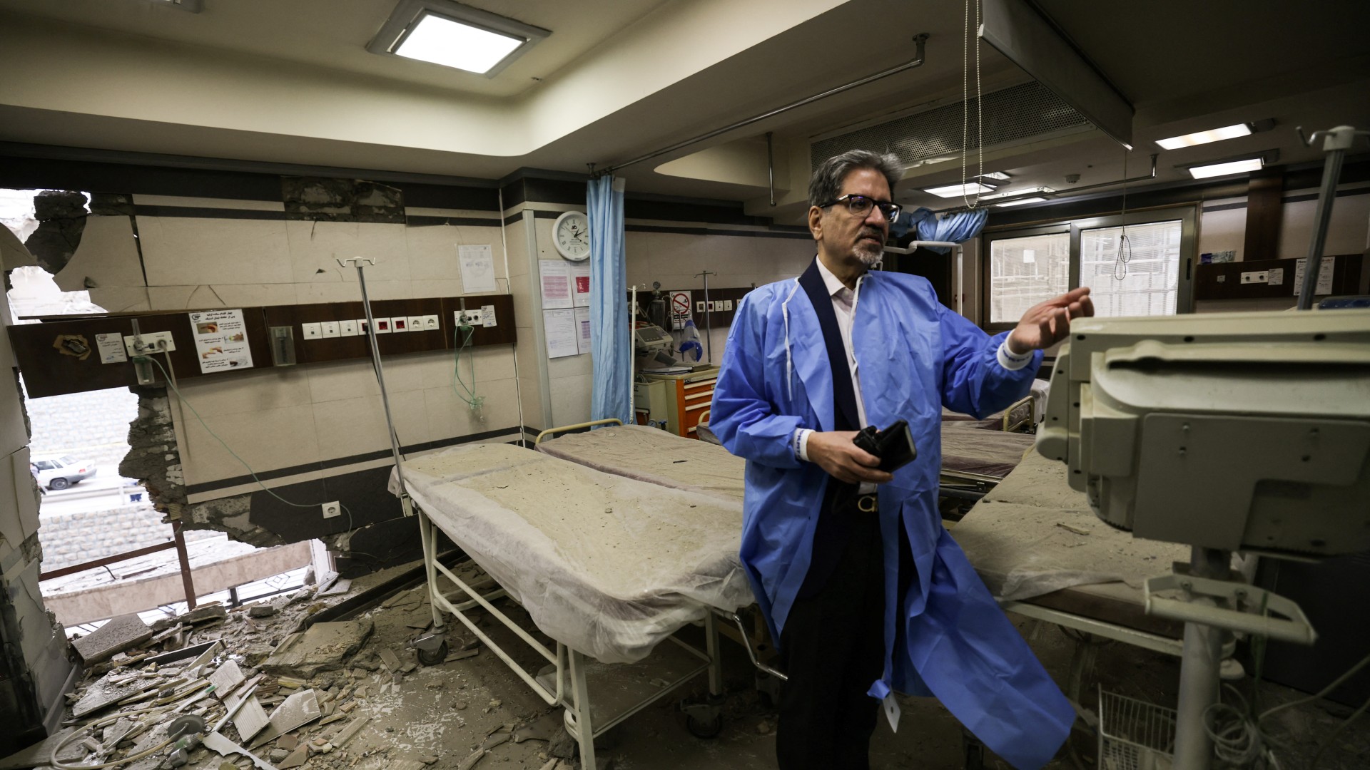 A doctor shows the damage inside Tehran's Gandhi Hospital, which was hit by a strike on 1 March (Atta Kenare/AFP)