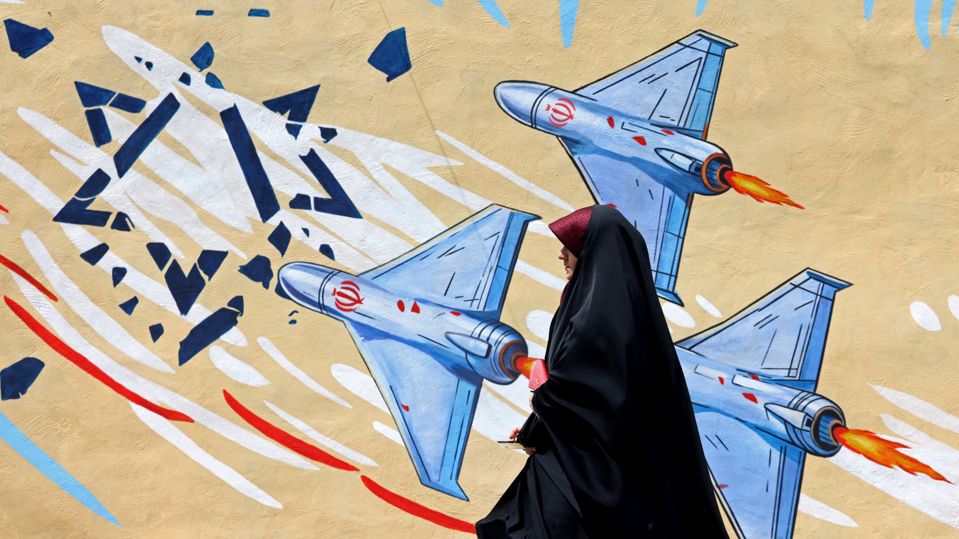A woman walks past an anti-US and anti-Israel mural, in Tehran on 8 April 2026 (Atta Kenare)
