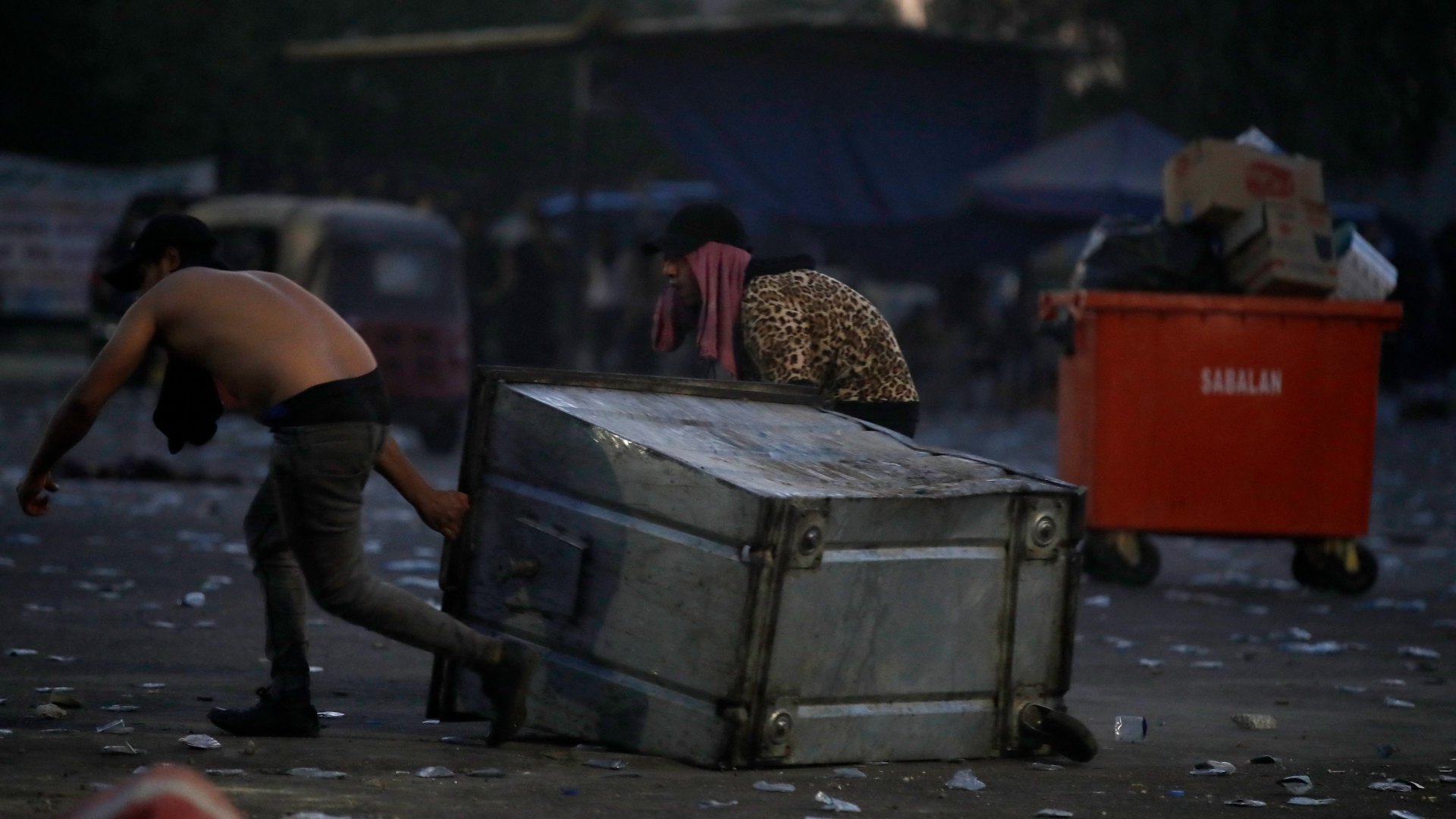 Supporters of Iraqi Shiite cleric Muqtada al-Sadr drag a trash bin to use as cover in the capital Baghdad.