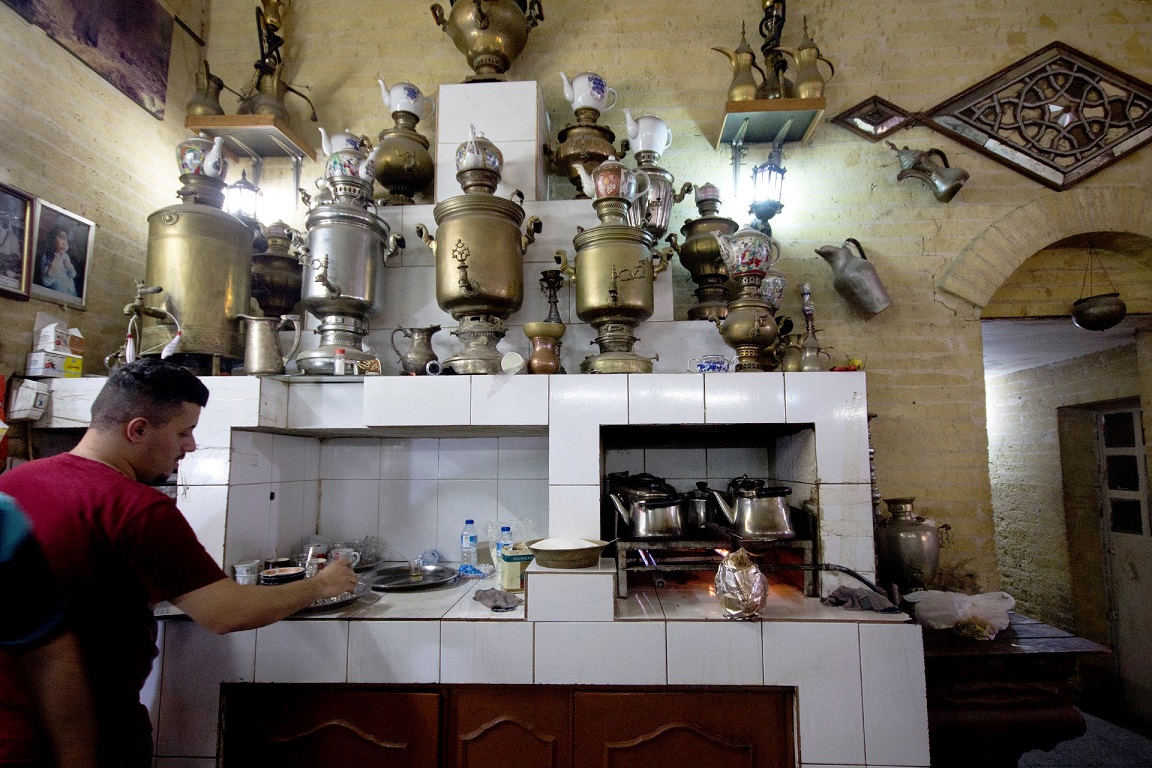 The wall of the legendary Shabandar cafe on Mutanabi Street is covered in old portraits and tea urns (MEE/Charlotte Mayhew)