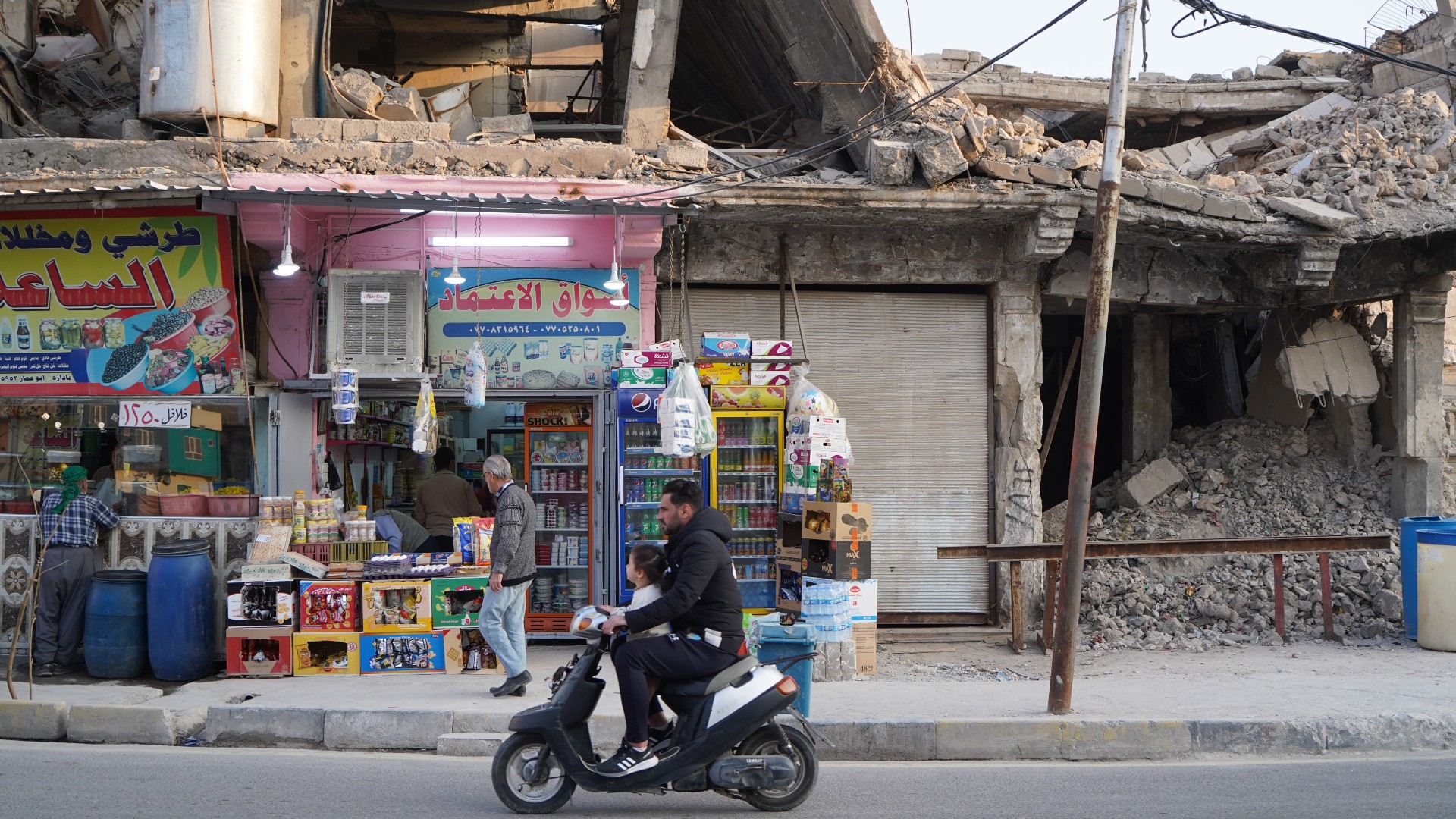 An Iraqi man rides his moped on 20 March 2023 near buildings destroyed years earlier in the battle against the Islamic State group in Mosul in northern Iraq (MEE/Ismael Adnan)