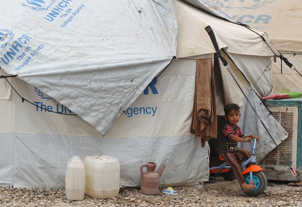 A boy rides a tricycle outside a tent at Iraq’s Laylan camp for displaced people on 9 May (AFP) 