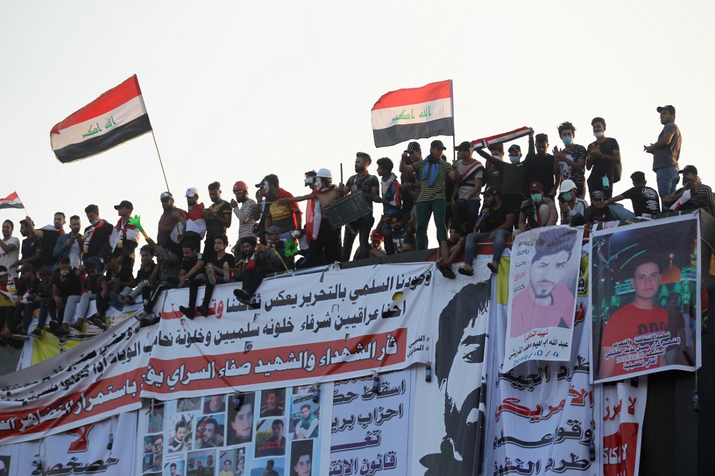 Iraqi demonstrators stand atop an abandoned building in Baghdad on 31 October (AFP)