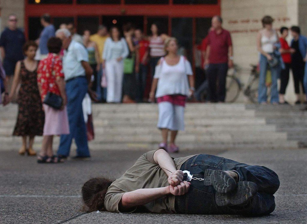 Un activiste reproduit l’une des techniques utilisées pour extorquer des informations aux prisonniers dans les prisons israéliennes à Tel Aviv en 2004 (AFP)