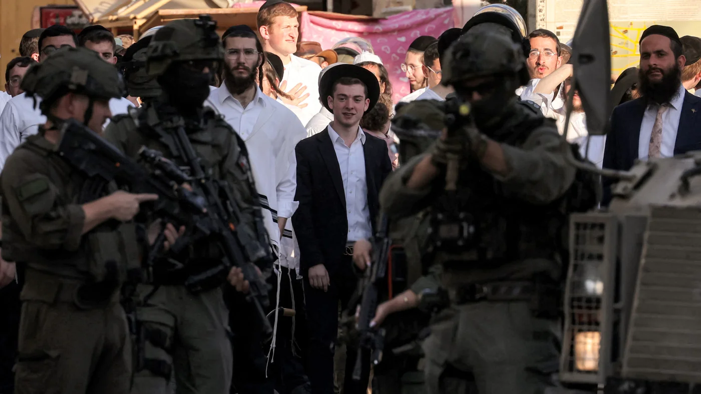 Israeli soldiers stand guard as settlers tour the old city centre and market of Hebron in the occupied West Bank, on 28 June 2025 (AFP)