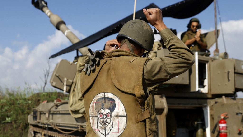 An Israeli soldier wears a patch on the back of his jacket showing Hezbollah leader Hassan Nasrallah as a target, in northern Israel on 4 January 2024 (Jalaa Marey/AFP)