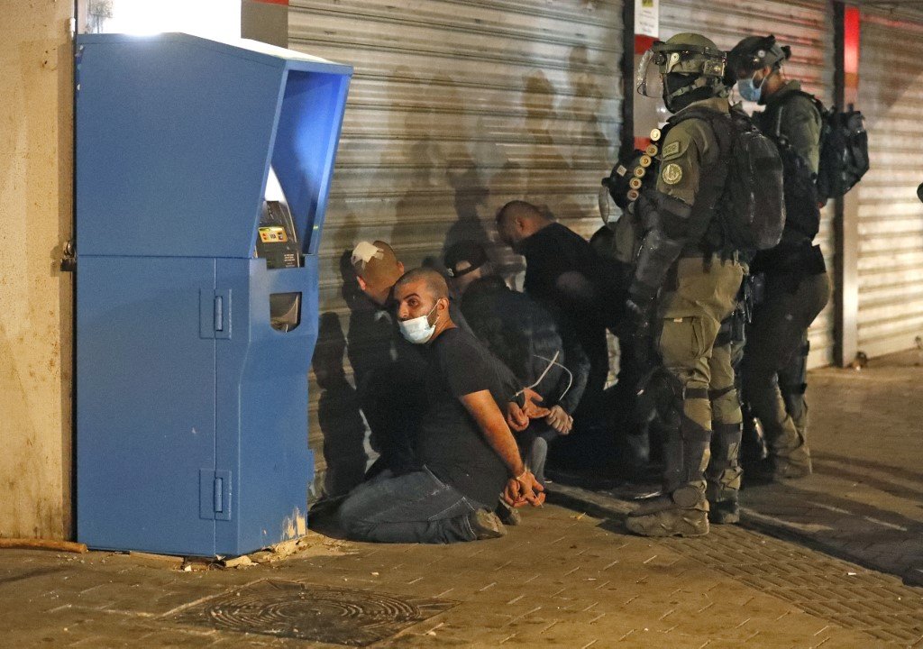 Les forces israéliennes arrêtent un groupe de citoyens palestiniens d’Israël à Lod, le 13&nbsp;mai, lors d’un saccage par des extrémistes israéliens et des manifestations de Palestiniens (AFP)