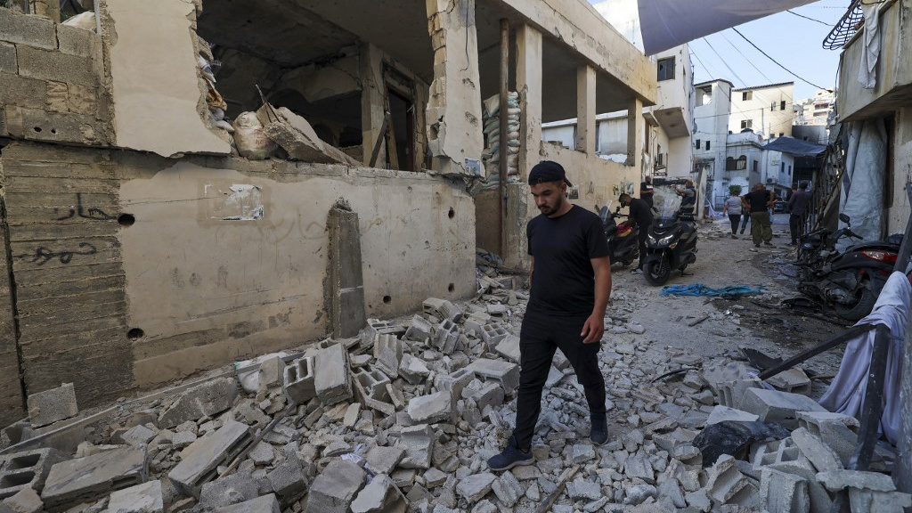 People walk by rubble in Jenin, in the occupied West Bank, on 5 July 2023 (AFP)