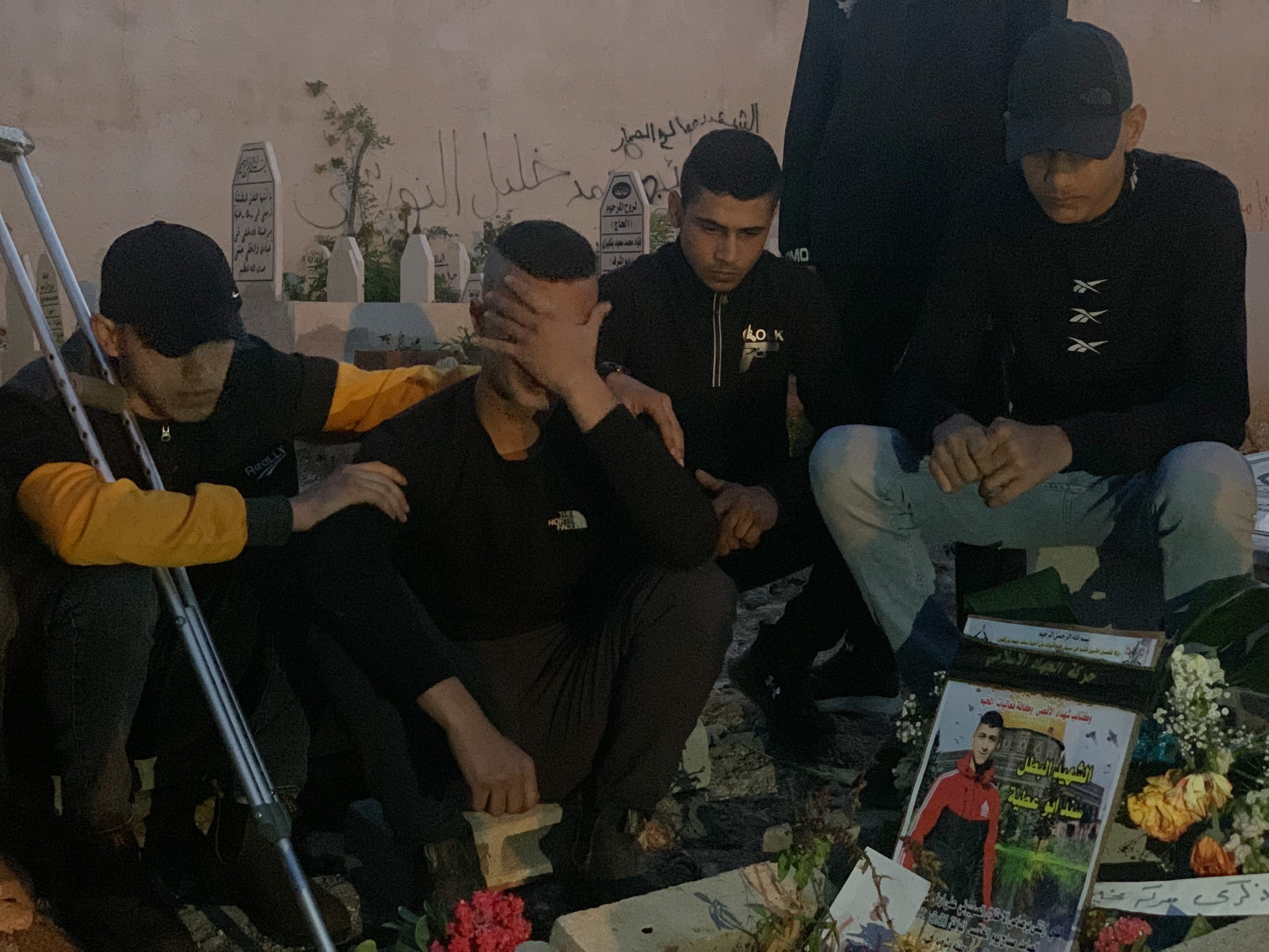 Sami being consoled near Sanad's grave. (MEE/Shatha Hammad)