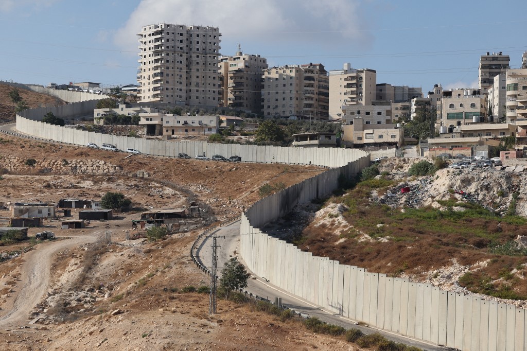Israeli forces are stationed by the separation wall with a view of the Palestinian Shuafat refugee camp in occupied East Jerusalem in October 2022 (AFP)