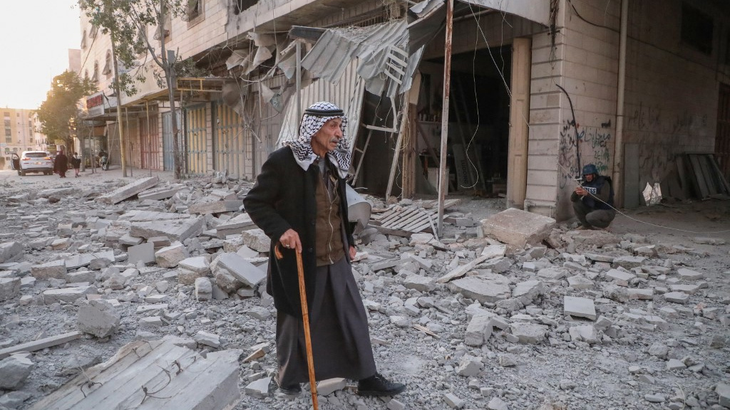 A Palestinian man walks on the rubble of a home demolished by Israeli forces during a raid in Hebron, in the occupied West Bank, on 21 January 2024 (Mosab Shawer/AFP)