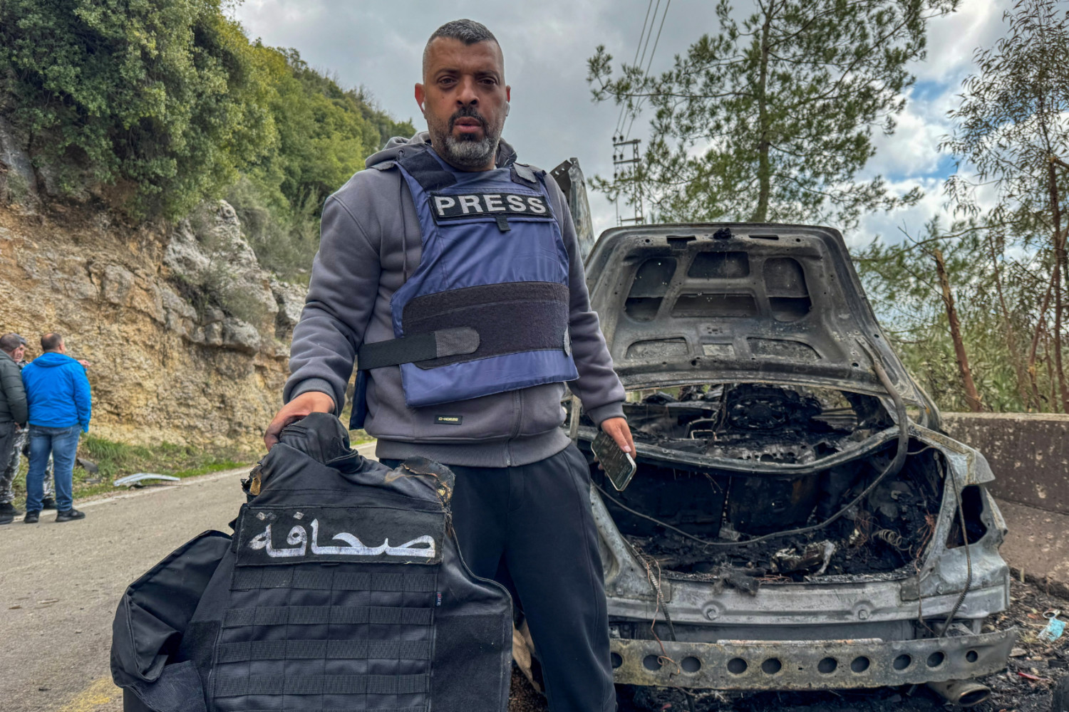 Al Mayadeen journalist Jamal Al-Gharabi holds a press vest next to a car destroyed by a targeted Israeli strike that killed Lebanese journalists Al Mayadeen reporter Fatima Ftouni and cameraman Mohammed Ftouni, and Al Manar reporter Ali Choueib on 28 March 2026 (Reuters)