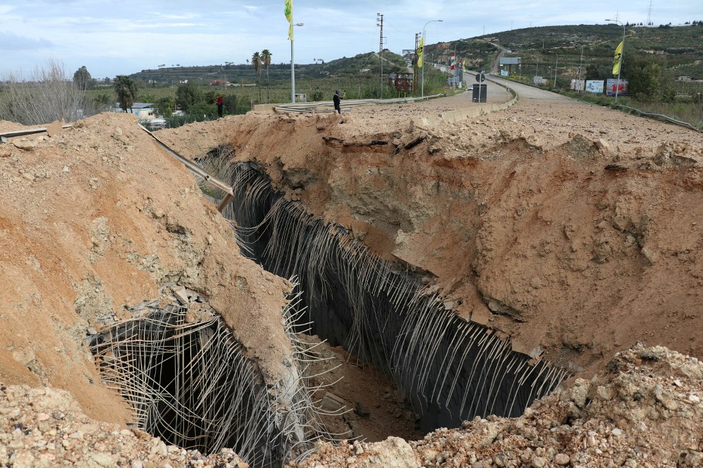 A man stands near the crater the day after an Israeli air strike targeted the Qasmiyeh Bridge in southern Lebanon on 23 March, 2026. (AFP)