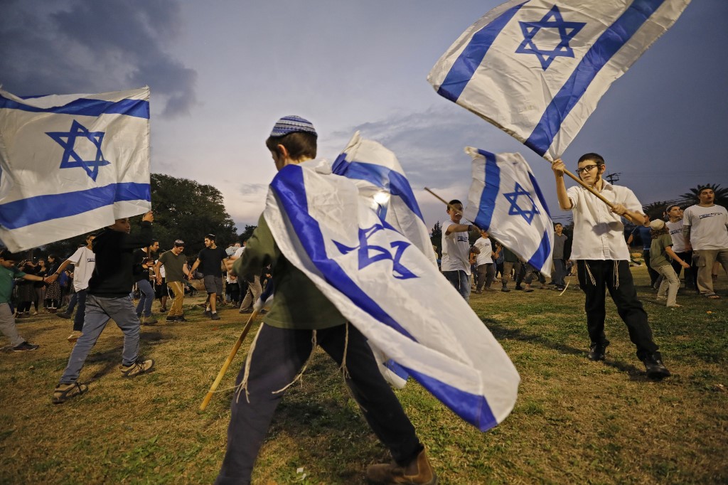 Israelis gather in the settlement of Mehola in the occupied West Bank on 3 February to welcome a convoy of settlers calling to implement the ‘deal of the century’ (AFP)