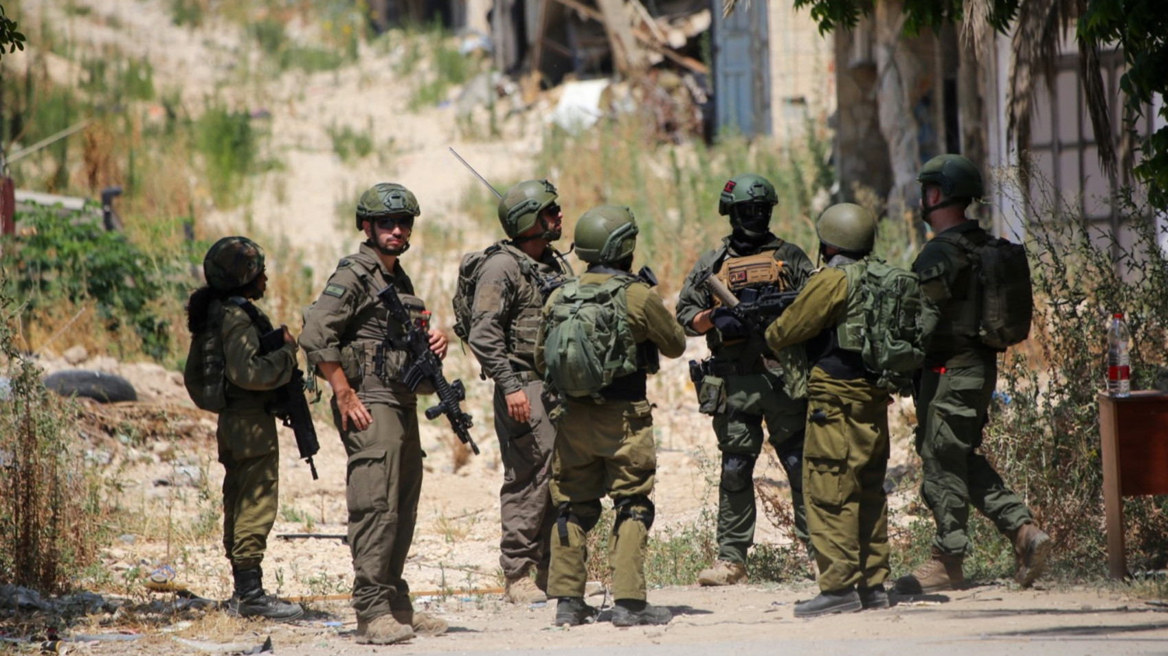 Israeli forces stand guard as Palestinian families visit the homes they were forced to abandon during Israel's 'Iron Wall' operation in the Tulkarm refugee camp, 17 June 2026 (Mojahid Nawahda/MEE)