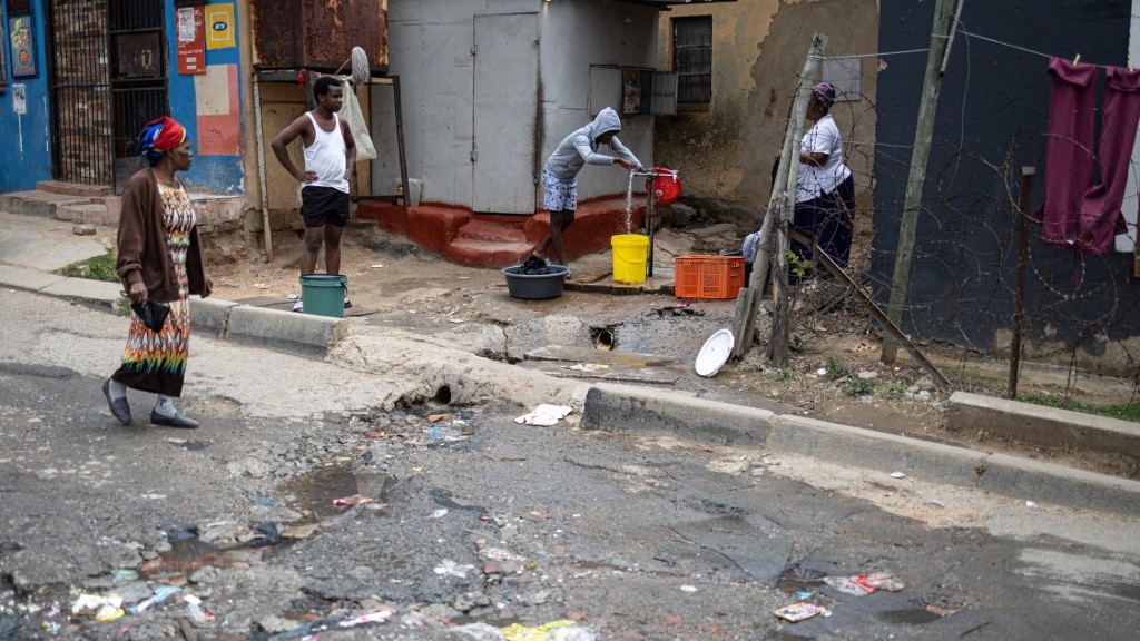 Residents fill up buckets of water from a communal tap in Alexandra, near Johannesburg, on October 5, 2026. (EMMANUEL CROSET / AFP)