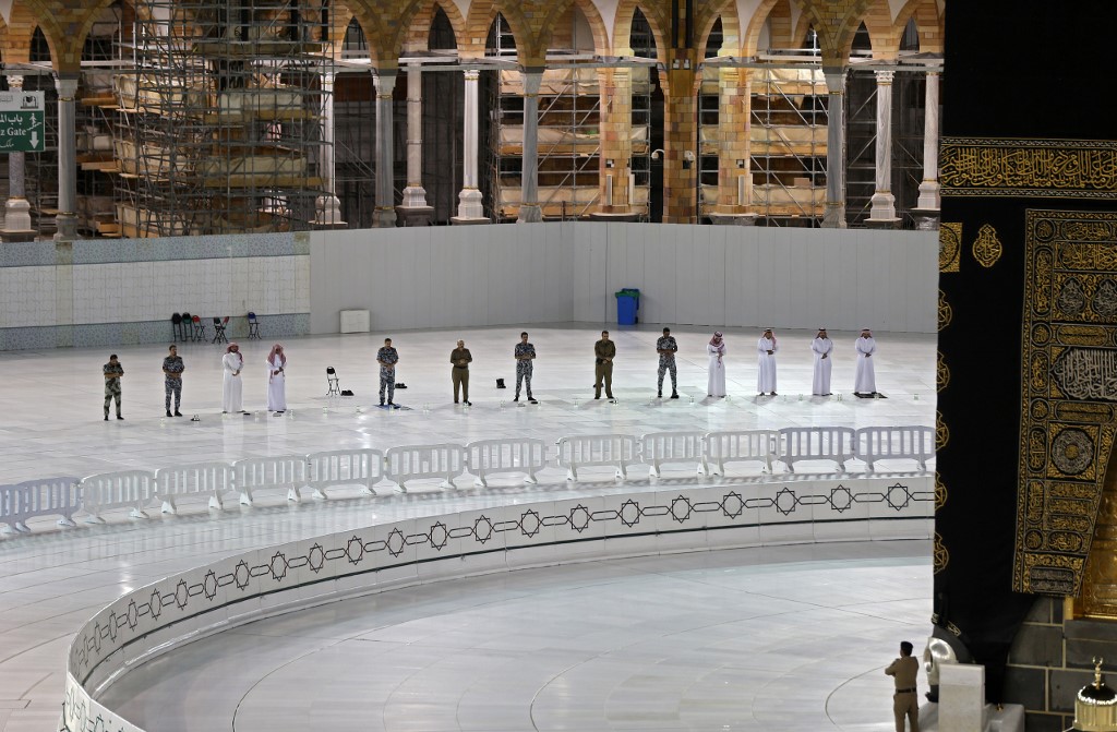 Worshippers perform prayers while keeping distance between them next to the Kaaba in Mecca’s Grand Mosque on 27 April (AFP)