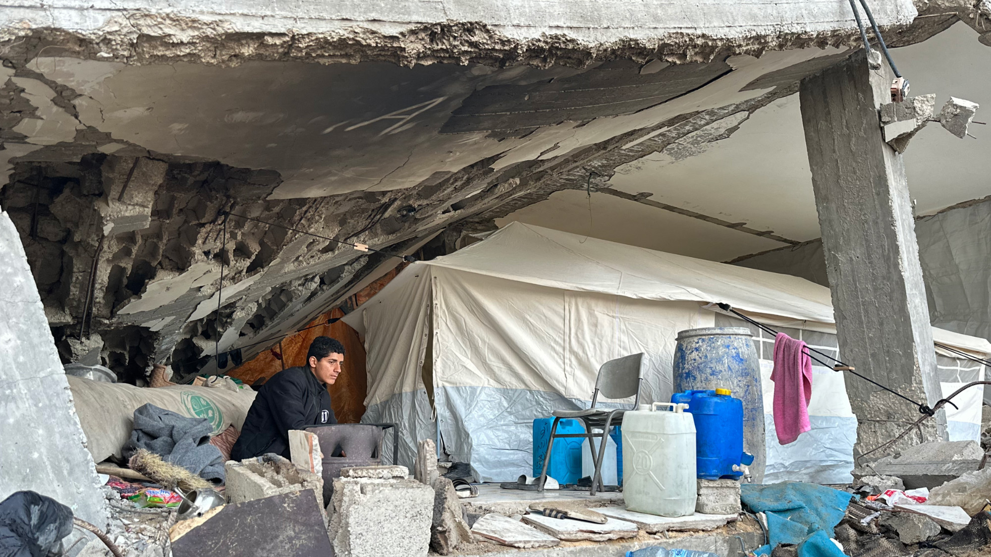 Linda Jarour point to a hole in her tent in Gaza City (MEE/Ahmed Dremly)