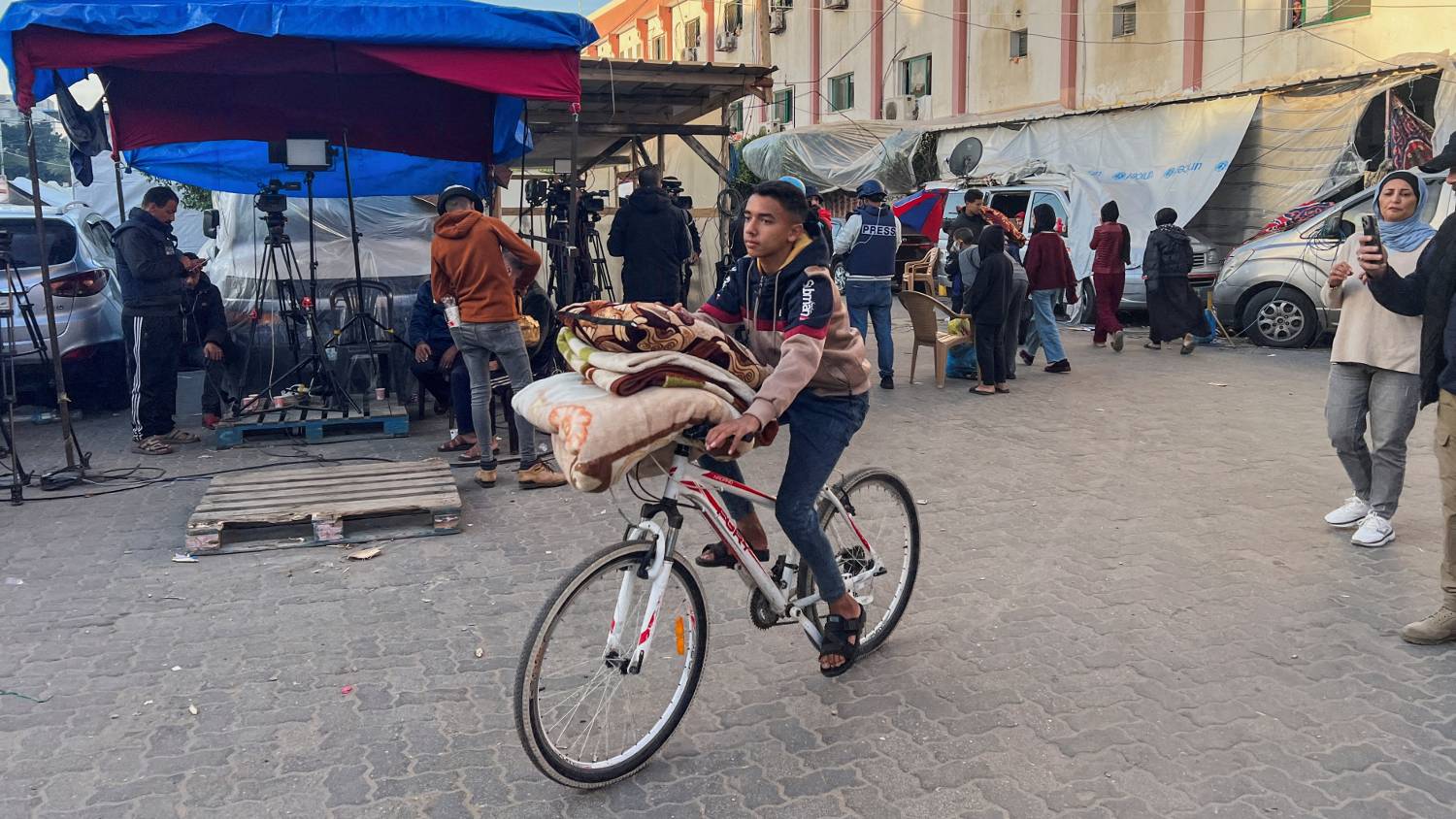 A displaced Palestinian, who fled his house due to Israeli strikes, rides his bicycle with belongings as he leaves Nasser hospital during a temporary truce between Hamas and Israel, in Khan Younis in the southern&nbsp;Gaza&nbsp;Strip on 24 Novemeber 2023.