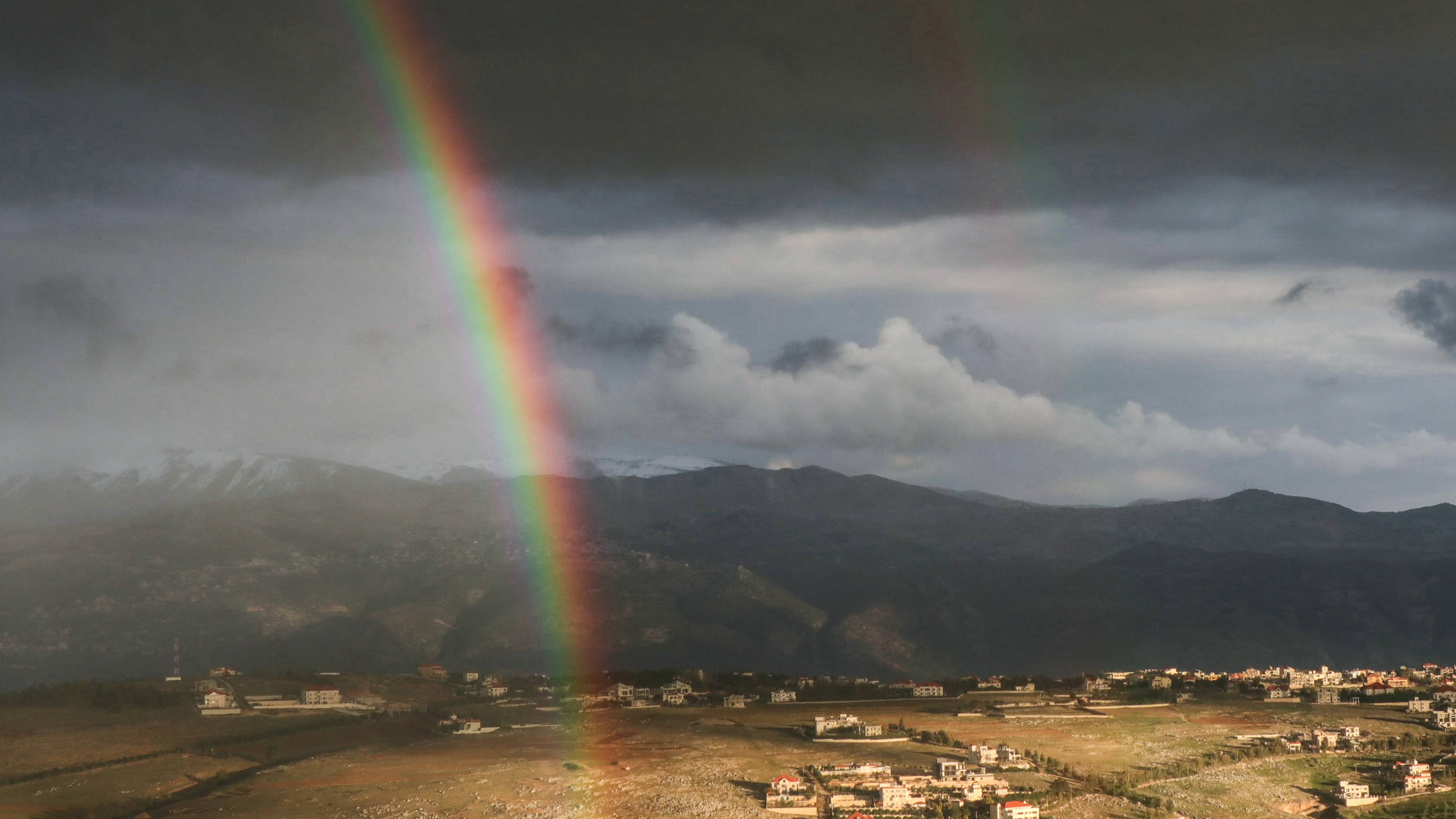 A rainbow rises near the southern Lebanese border town of Khiam on 24 January 2025 (Rabih Daher/AFP) 